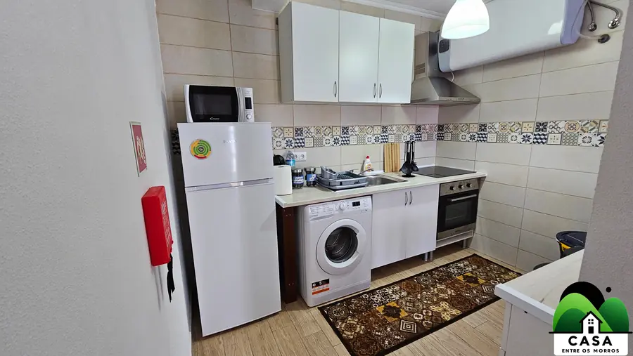 Cozinha com azulejos padronizados, fogão, forno e máquina de lavar roupa