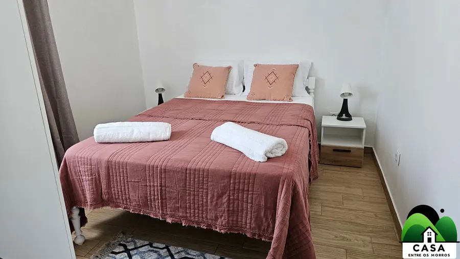 Quarto com roupeiro branco, cadeira preta e cortinas